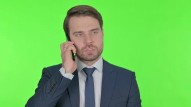 Young Adult Businessman Talking Angry on Phone on Green Background 