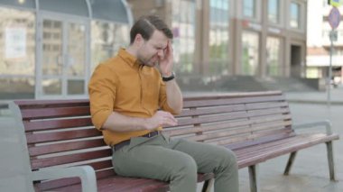 Casual Young Man with Headache Sitting Outdoor on Bench