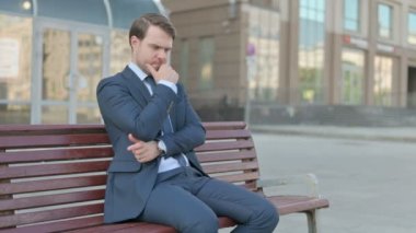 Pensive Young Businessman Thinking while Sitting Outdoor on Bench