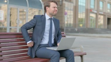 Middle Aged Businessman with Back Pain Using Laptop while Sitting Outdoor on Bench