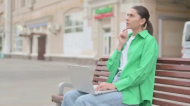 Thinking Young Woman Using Laptop while Sitting Outdoor on Bench
