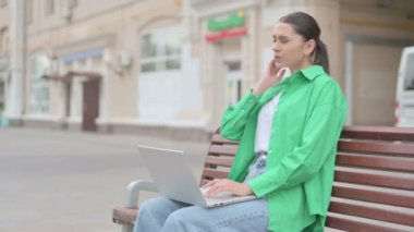Young Woman with Neck Pain Using Laptop while Sitting Outdoor on Bench