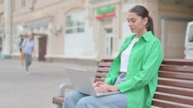 Coughing Young Woman Using Laptop while Sitting Outdoor on Bench