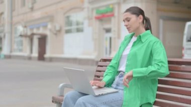 Young Woman with Back Pain Using Laptop while Sitting Outdoor on Bench