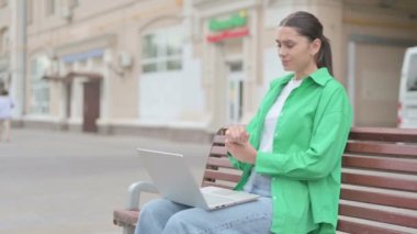 Young Woman with Wrist Pain Using Laptop while Sitting on Bench