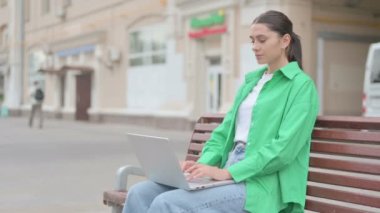 Young Woman with Headache Using Laptop while Sitting Outdoor on Bench