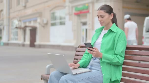 Young Woman Using Smartphone Laptop While Sitting Outdoor Bench — Stockvideo