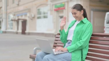 Young Woman Talking on Video Call while Sitting Outdoor on Bench
