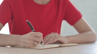 Close Up of Young Woman Writing on Notebook
