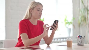 Young Woman Browsing Internet on Smartphone in Office 