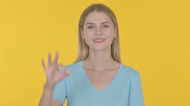 Casual Young Woman with Ok Sign on Yellow Background 