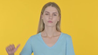Thumbs Down by Casual Young Woman on Yellow Background 
