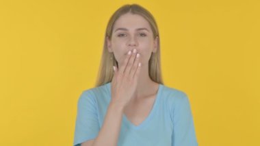 Flying Kiss by Casual Young Woman on Yellow Background 