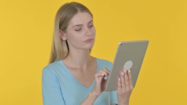 Casual Young Woman Celebrating Success on Tablet on Yellow Background 