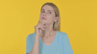 Pensive Casual Young Woman Thinking and getting Idea on Yellow Background 