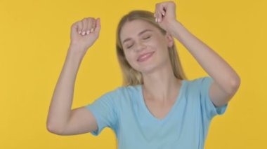 Casual Young Woman Dancing in Joy on Yellow Background 