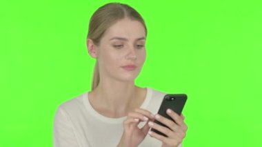 Casual Young Woman Celebrating on Smartphone on Green Background 