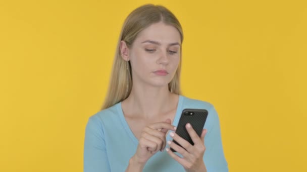 Casual Young Woman Browsing Smartphone Yellow Background — Vídeos de Stock