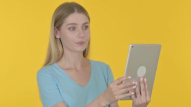 Video Call on Tablet by Casual Young Woman on Yellow Background 