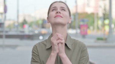 Young Woman Praying with Folded Hands while Standing Outdoor