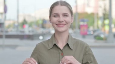Loving Young Woman showing Heart Shape by Hands Outdoor