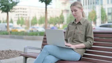 Busy Young Woman Using Laptop Sitting Outdoor on Bench