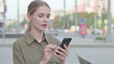 Upset Young Woman Reacting to Loss on Smartphone Outdoor