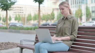 Young Woman with Laptop Looking at Camera while Sitting Outdoor on Bench
