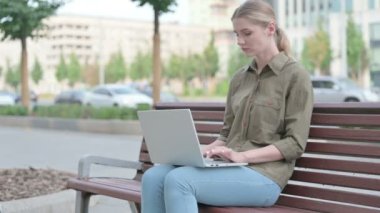 Young Woman Reacting to Loss on Laptop while Sitting Outdoor on Bench