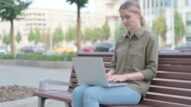 Coughing Young Woman Using Laptop while Sitting Outdoor on Bench