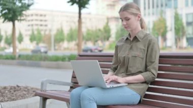 Rejecting Young Woman in Denial While using Laptop Sitting Outdoor on Bench 