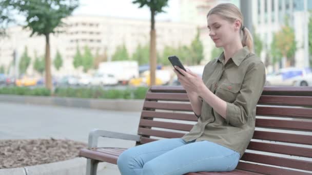 Young Woman Celebrating Online Success Smartphone While Sitting Outdoor Bench — 图库视频影像