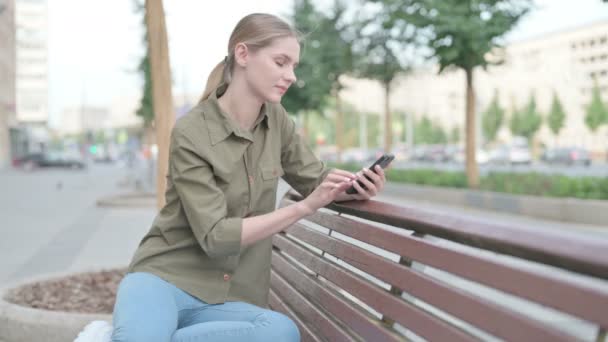 Young Woman Using Smartphone While Sitting Outdoor Bench — 图库视频影像