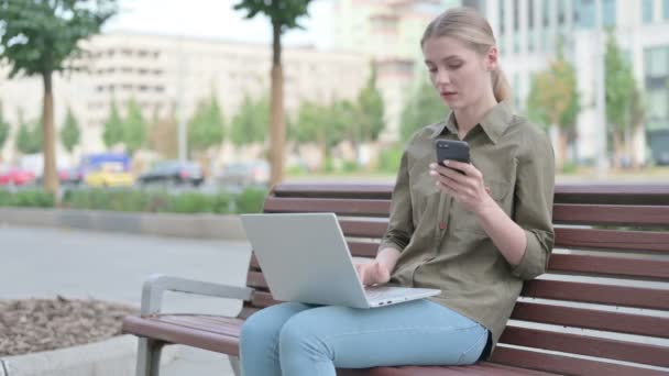 Young Woman Using Smartphone Laptop While Sitting Outdoor Bench — 图库视频影像