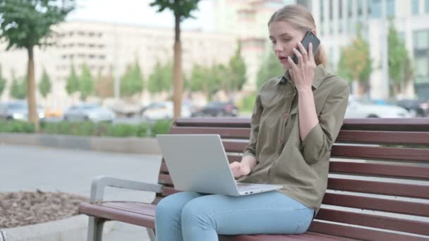 Angry Young Woman Talking Phone Using Laptop While Sitting Outdoor — 图库视频影像