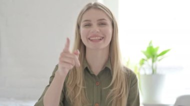 Sarışın genç kadın kamerayı işaret ediyor. 