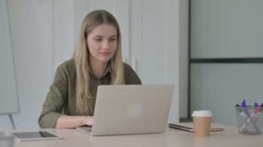 Ofiste dizüstü bilgisayar kullanırken Sarışın Genç Kadın Başarı Kutlaması