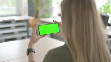 Sarışın Genç Kadın Yeşil Ekran ile Akıllı Telefon İzliyor 