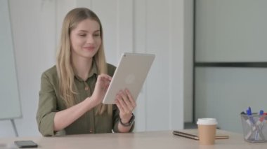 Ofiste otururken Tablet kullanan Sarışın Genç Kadın