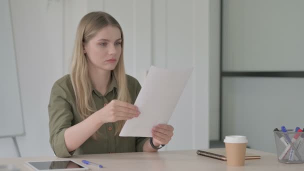 文書を読みながら損失に反応するブロンドの若い女性 — ストック動画