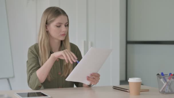 ブロンドの若い女性 オフィスで文書を読む — ストック動画
