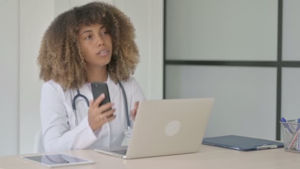 Dişi Afrikalı Doktor Laptop Çalışırken Telefonla Konuşuyor — Stok video