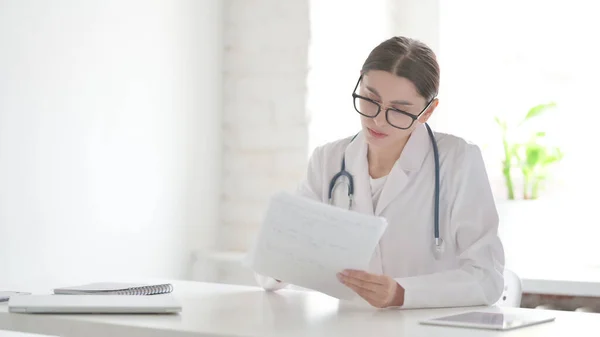 Young Female Doctor Reading Documents in Office