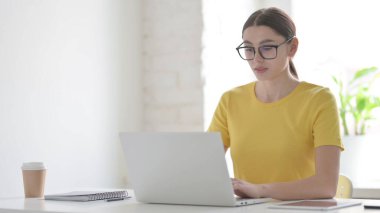 Ofiste dizüstü bilgisayarda çalışan çekici genç kadın.