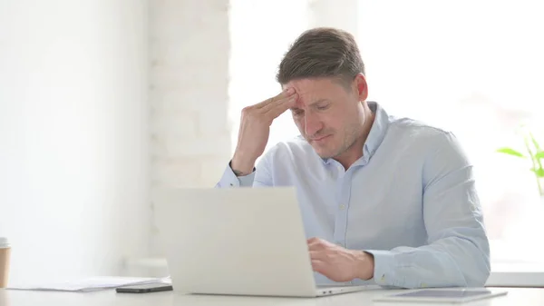 ラップトップで働いている間に頭痛を持っている中年の男性 — ストック写真