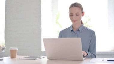 Ofiste dizüstü bilgisayarda çalışan çekici genç kadın.