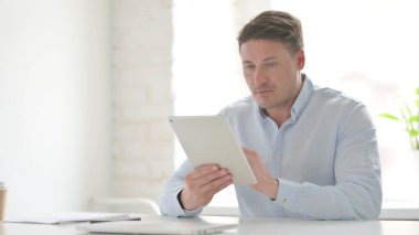 Ofiste otururken Tablet kullanan Orta Yaşlı Adam