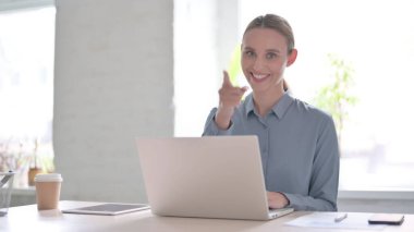 Ofiste dizüstü bilgisayar kullanırken Genç Kadın Kamerayı Gösteriyor