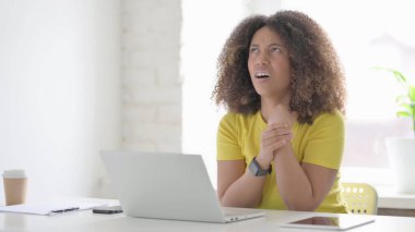 Ofiste dizüstü bilgisayar kullanırken bilek ağrısı çeken genç Afrikalı kadın.