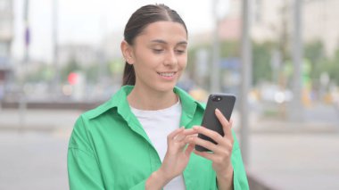 Young Woman Browsing Internet on Smartphone Outdoor